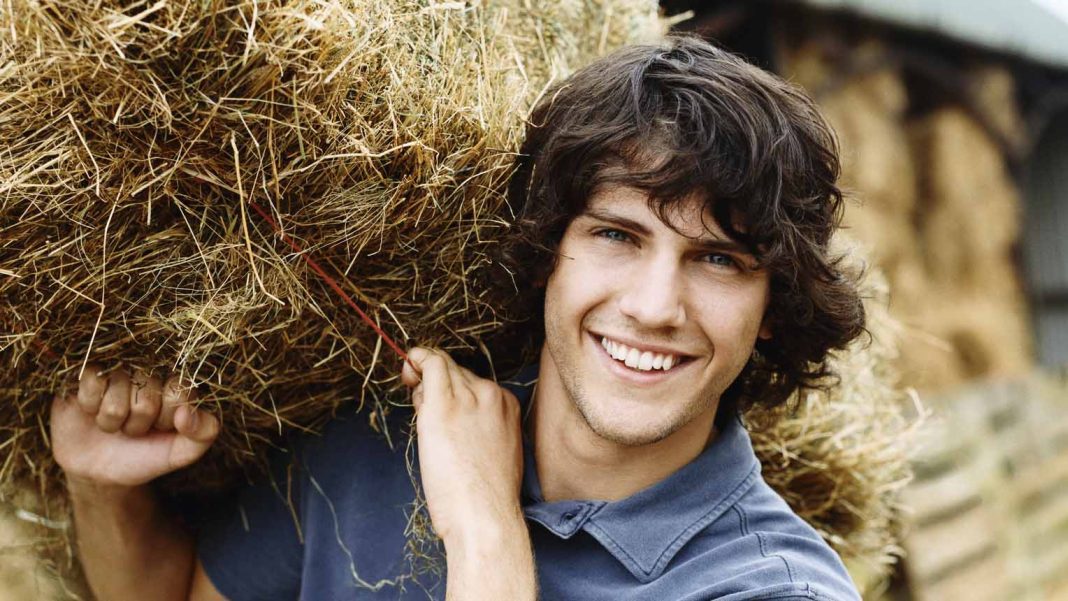 Young Farmer Carrying a Bale of Hay